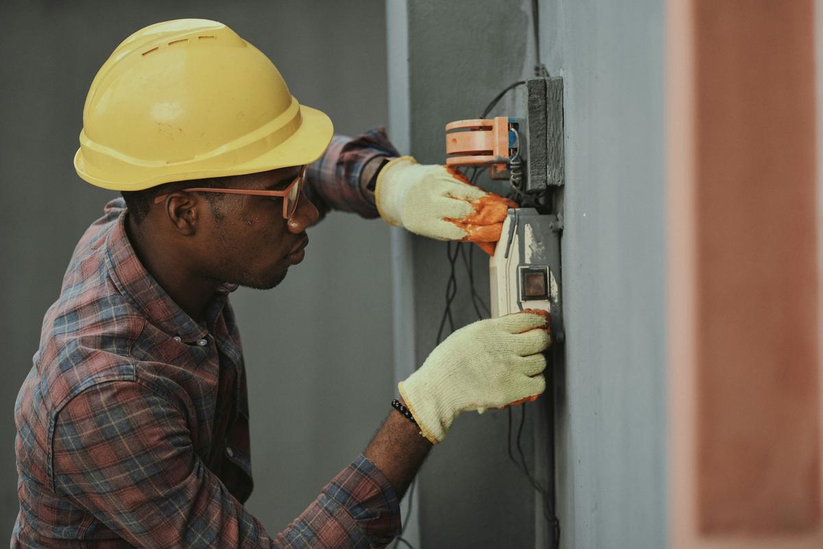 Electricians installing a distribution panel, shown against an electrical layout drawing